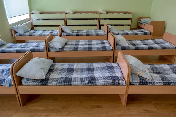 Muchas camas pequeñas en la guardería preescolar dormitorio vacío . — Foto de Stock