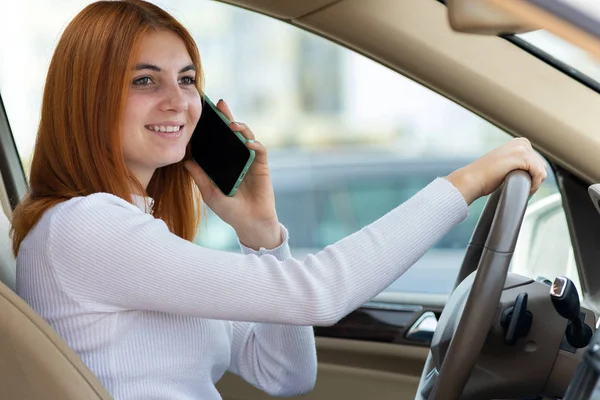 Счастливая рыжая девушка разговаривает по мобильному телефону за рулем — стоковое фото