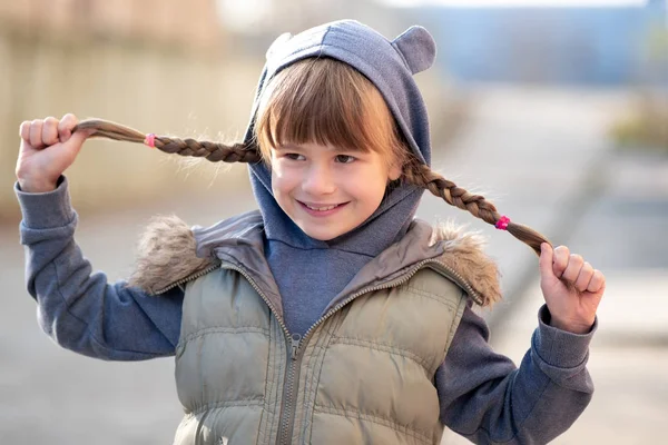 Портрет щасливої дівчинки з косами для волосся в теплому одязі — стокове фото
