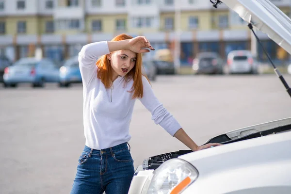 Joven mujer estresada conductor de pie cerca de coche roto con h abierto — Foto de Stock