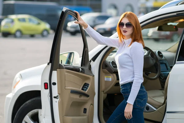 Yong bonita mujer de pie cerca de un gran coche todo terreno al aire libre . — Foto de Stock