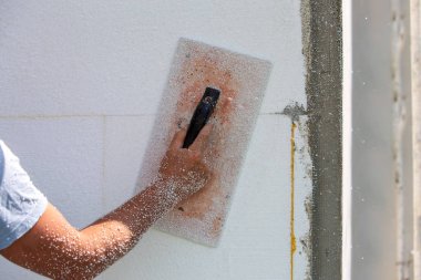 Zımparalamak ve pürüzsüz yapmak için aletleri olan bir işçinin eli.