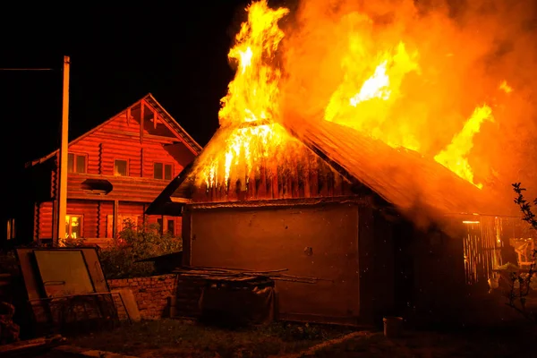 Casa de madera o granero ardiendo en llamas por la noche . — Foto de Stock