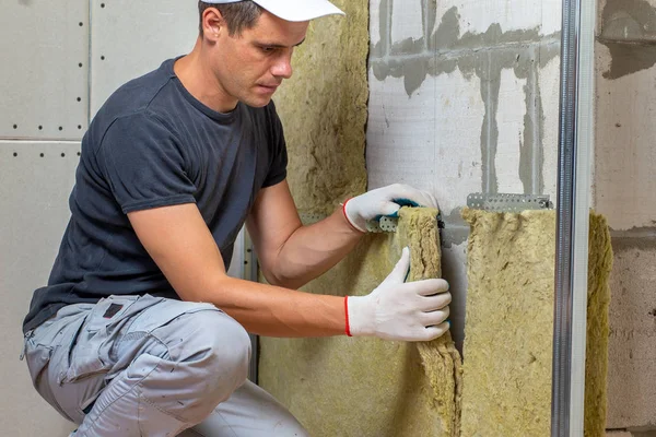 Werknemer die een kamerwand isoleert met thermische elementen van minerale steenwol — Stockfoto