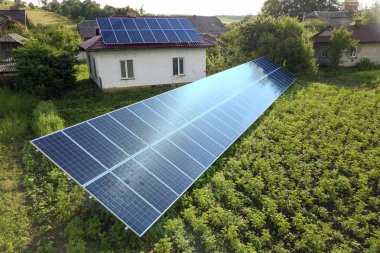 Temiz enerji için mavi güneş panelleri ile bir evin havadan görünümü.