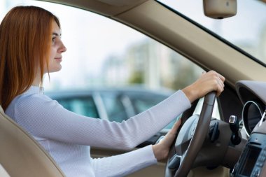 Genç kızıl saçlı kadın araba kullanıyor..