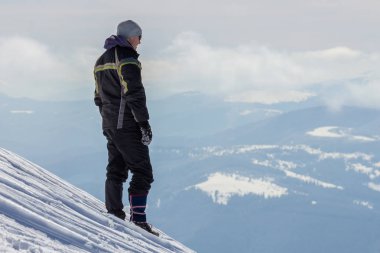 Karlı dağın tepesinde tek başına duran turistin silueti keyfini çıkar.