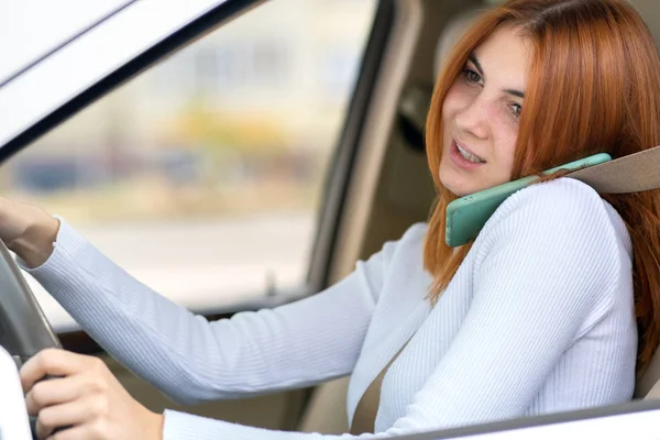 Šťastná zrzka dívka mluví na svém mobilním telefonu za volantem — Stock fotografie