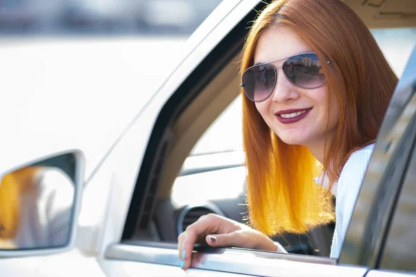 Joven mujer bonita conductor en gafas de sol mirando hacia fuera el coche fron — Foto de Stock