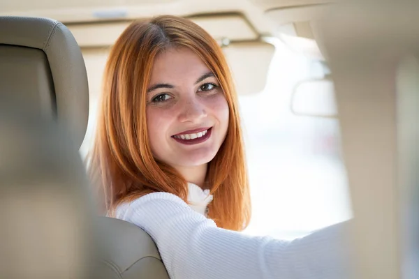 Молодая рыжая женщина водитель за рулем автомобиля счастливо улыбается . — стоковое фото
