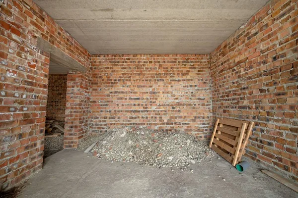 Interior of unfinished brick house with concrete floor and bare