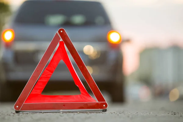 Triângulo de emergência vermelho parar sinal e carro quebrado em uma rua da cidade — Fotografia de Stock