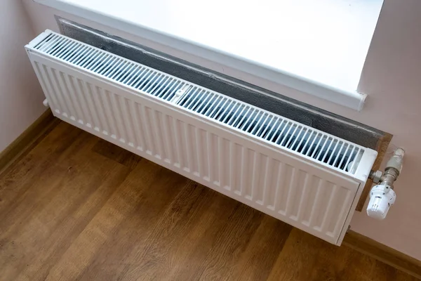 White metal heating radiator mounted on a wall in room interior. Stock Image