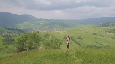 Genç kadın bir yaz günü dağ manzarasının tadını çıkarıyor. Doğa ortamında dinlenme ve meditasyon.