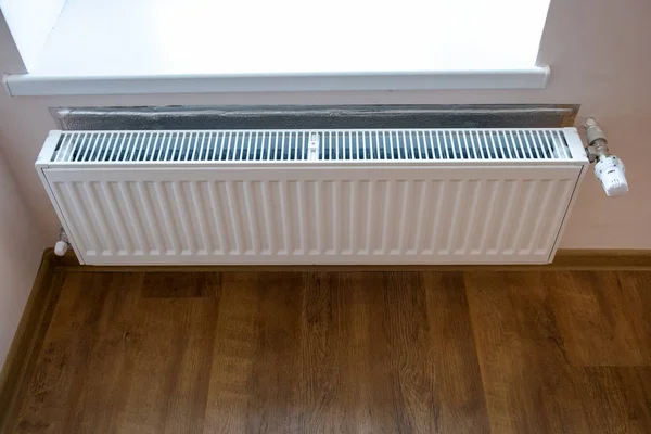 White metal heating radiator mounted on a wall in room interior. Stock Photo