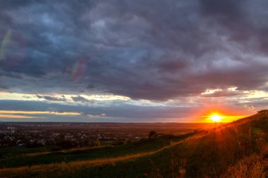 Uzak otlar üzerinde dramatik bulutlar içinde gün batımı 