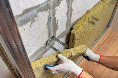 Bir oda duvarını mineral kaya yünleriyle yalıtan işçiler.