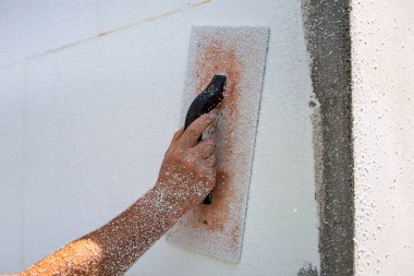 Zımparalamak ve pürüzsüz yapmak için aletleri olan bir işçinin eli.