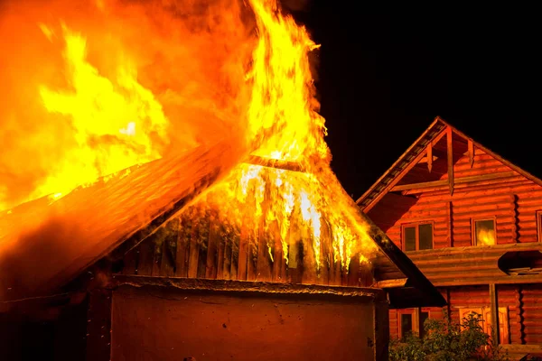 Casa de madeira ou celeiro queimando em chamas à noite . — Fotografia de Stock