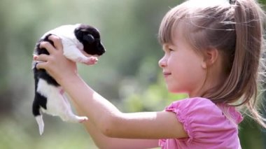Güzel bir kız çocuğu yazın dışarıda köpek yavrusuyla oynuyor..