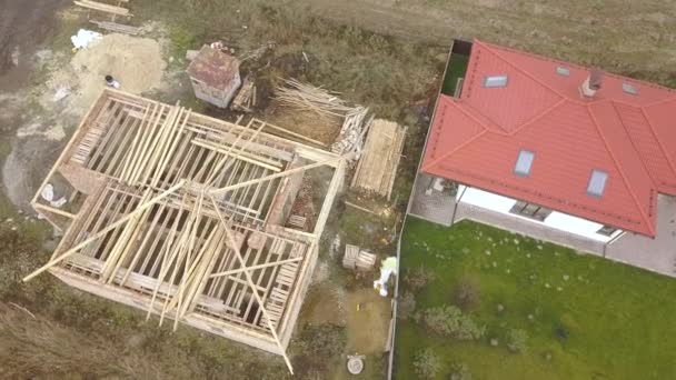 Top down aerial view of two private houses, one under construction with wooden roofing frame and another finished with red tiled roof. — Stock Footage Top Aerial View Two Private Houses One Construction Wooden Roofing Royalty Free Stock Footage