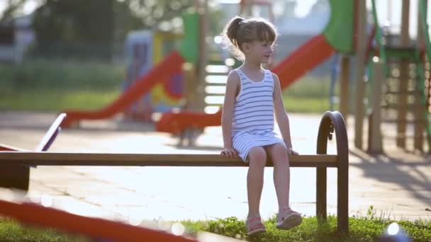 Nettes Mädchen Das Auf Einer Bank Auf Dem Sommerspielplatz Kindergartenhof — Stockvideo