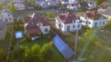 Çatıda güneş panelleri ve rüzgar jeneratörü olan özel bir evin havadan görüntüsü..