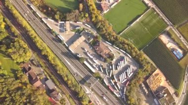 Otoban yolunun yukarıdan aşağı manzaralı ve hızlı giden trafiği ve park yerini park etmiş kamyonları olan..