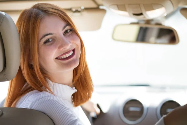 Молодая рыжая женщина водитель за рулем автомобиля счастливо улыбается . — стоковое фото