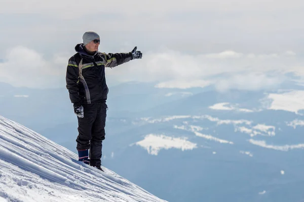 Silhouette eines einsamen Touristen, der auf einem schneebedeckten Berggipfel in — Stockfoto
