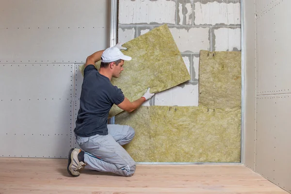 Arbeiter isoliert eine Raumwand mit Mineralwolle — Stockfoto