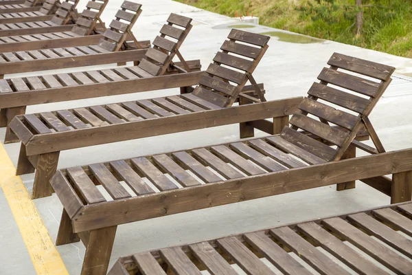Fila de sillas de playa de madera vacías cerca del agua al aire libre . — Foto de Stock