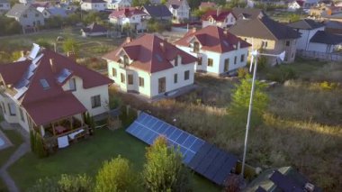 Çatıda güneş panelleri ve rüzgar jeneratörü olan özel bir evin havadan görüntüsü..