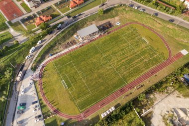 Yeşil kaplı bir stadyumdaki futbol sahasının havadan görünüşü. 