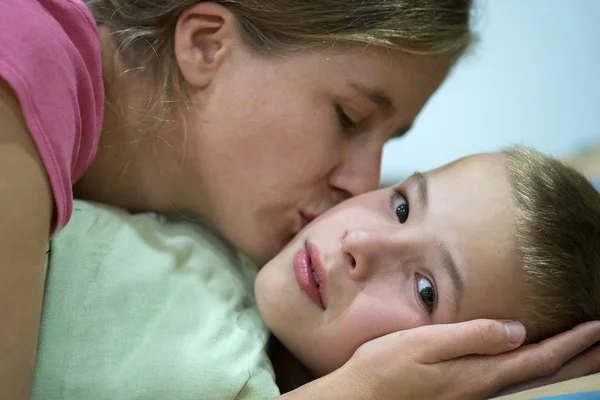 Happy mother gives her son a kiss before sleep and wish good nig — Stock Photo, Image