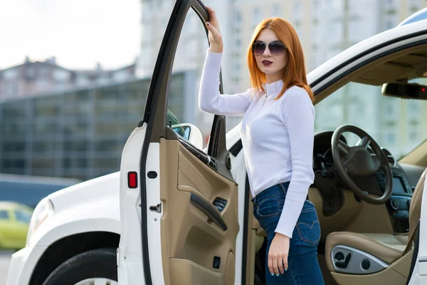 Yong bonita mujer de pie cerca de un gran coche todo terreno al aire libre . — Foto de Stock