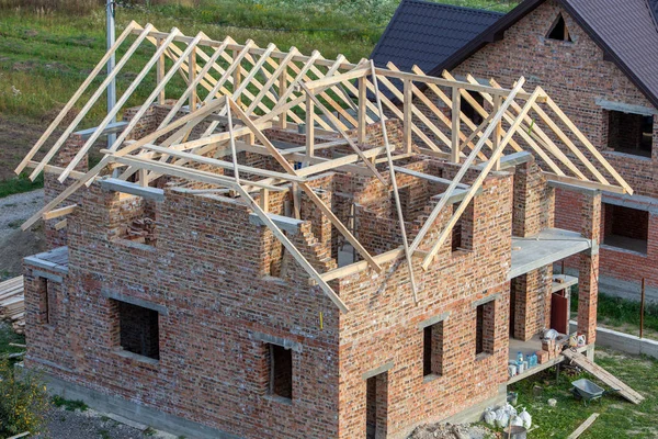 Casa de ladrillo sin terminar con estructura de techo de madera bajo construc — Foto de Stock