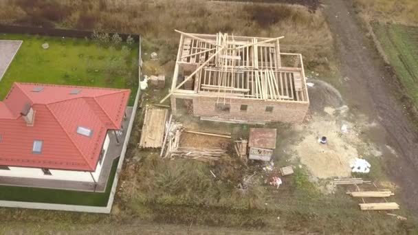 Top down aerial view of two private houses, one under construction with wooden roofing frame and another finished with red tiled roof. — Stock Footage Top Aerial View Two Private Houses One Construction Wooden Roofing Video Clip