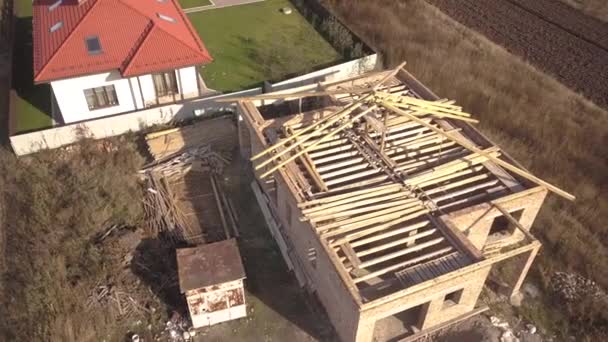 Top down aerial view of two private houses, one under construction with wooden roofing frame and another finished with red tiled roof. — Stock Footage Top Aerial View Two Private Houses One Construction Wooden Roofing Video Clip