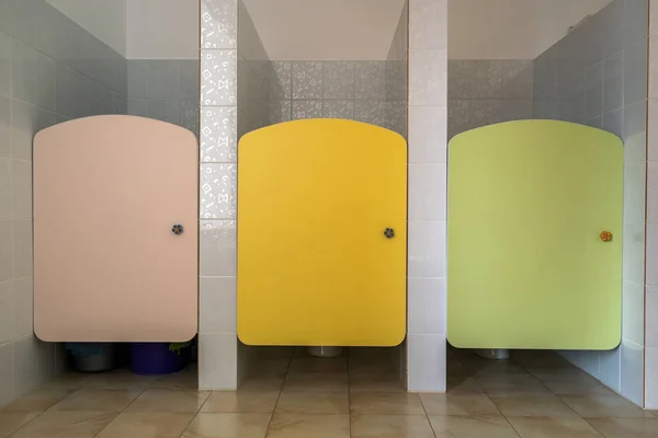 Puertas coloridas del inodoro en el interior del baño de la escuela primaria . —  Fotos de Stock