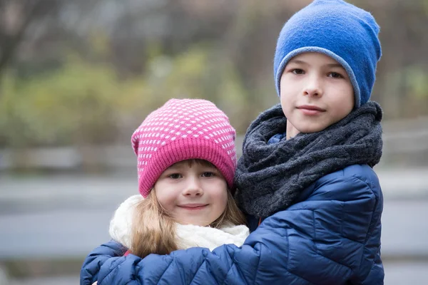 Twee kinderen jongen en meisje knuffelen elkaar buiten dragen wa — Stockfoto