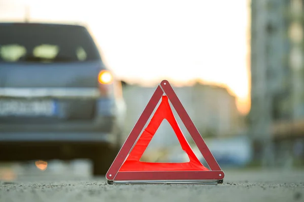 Red emergency triangle stop sign and broken car on a city street — Stock Photo, Image