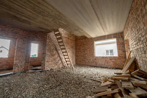 Interior of unfinished brick house with concrete floor and bare