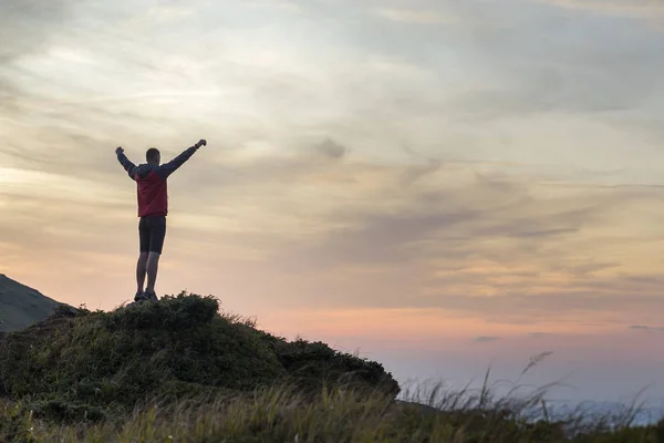 Silueta oscura de un excursionista escalando una montaña al atardecer — Foto de Stock