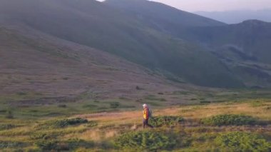 Sırt çantalı bir turist Carpathian dağlarında dağ yolunda koşuyor. Erkek turist kayalık çöl arazisinde koşuyor..