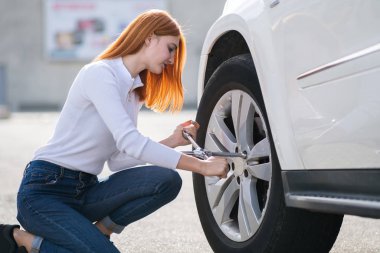 Kırık bir arabanın tekerlek değiştiren anahtarı olan genç bir kadın..