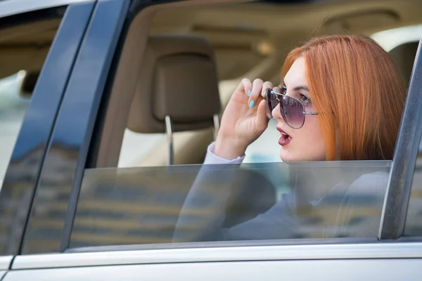 Молодая женщина с рыжими волосами и солнцезащитными очками едет на машине. Pas — стоковое фото