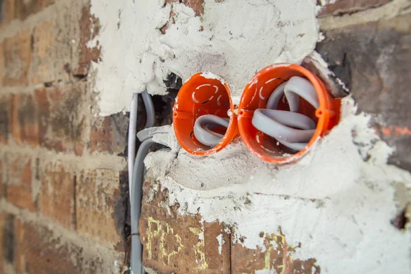 Enchufe cajas naranjas con cables en una pared. Instalación de cableado o — Foto de Stock