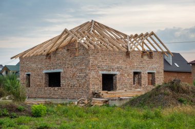 Ahşap çatılı, tamamlanmamış tuğla evi olan bir inşaat alanı.