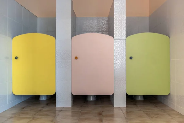 Portas de banheiro coloridas no interior do banheiro da escola primária . — Fotografia de Stock